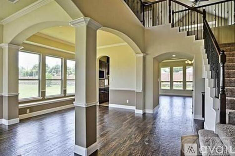 A spacious foyer with a staircase and arched columns.