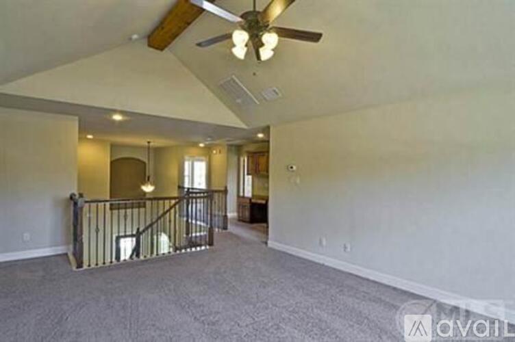 A spacious living room with a staircase and a ceiling fan.