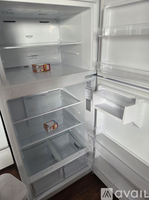 A white refrigerator with the door open and a box of milk on the door.
