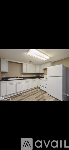 A kitchen with white cabinets and a wooden floor.