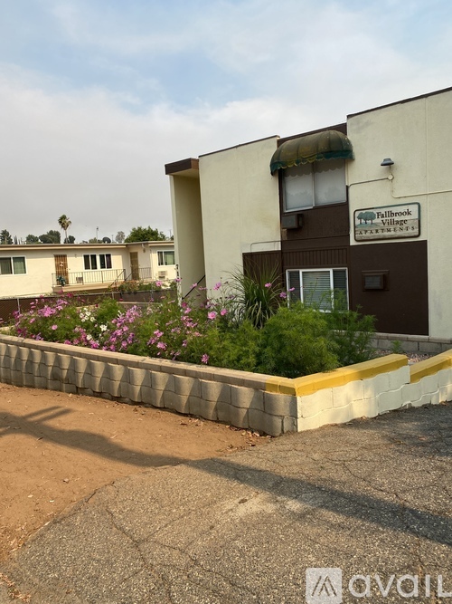 A building with a sign that says "Bullbrook Village" is surrounded by a flower bed.