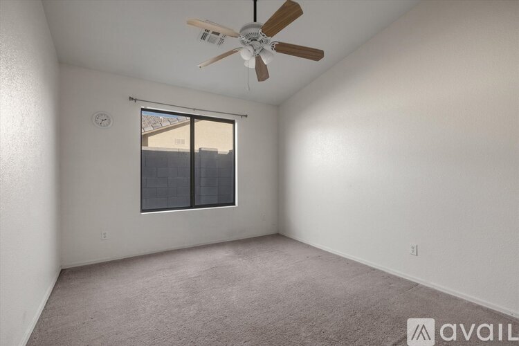 A room with a ceiling fan and a window with a view of a building outside.