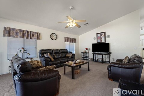 A living room with a black leather couch and a television.