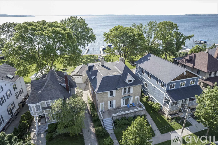 A bird's eye view of a house with a large front yard and a body of water in the background.