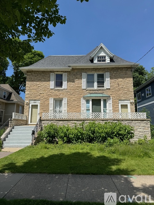 A two-story house with a stone facade and a green awning.