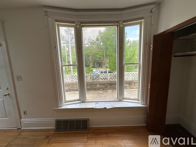 A room with a window showing a view of a park and a building.