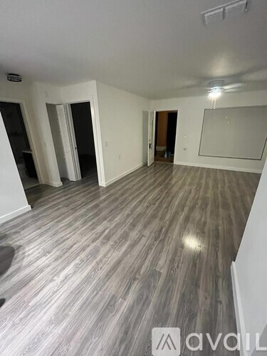 A room with wooden flooring and white walls, with a large mirror on the wall.