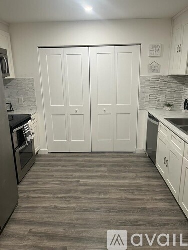 A kitchen with white cabinets and a grey floor.