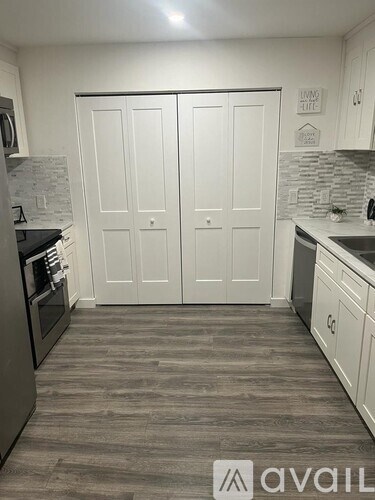 A kitchen with white cabinets and a grey floor.
