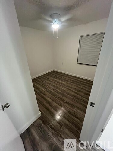 A room with wooden flooring and a window with blinds.