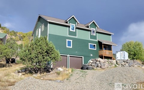 A green house with a garage and a balcony.