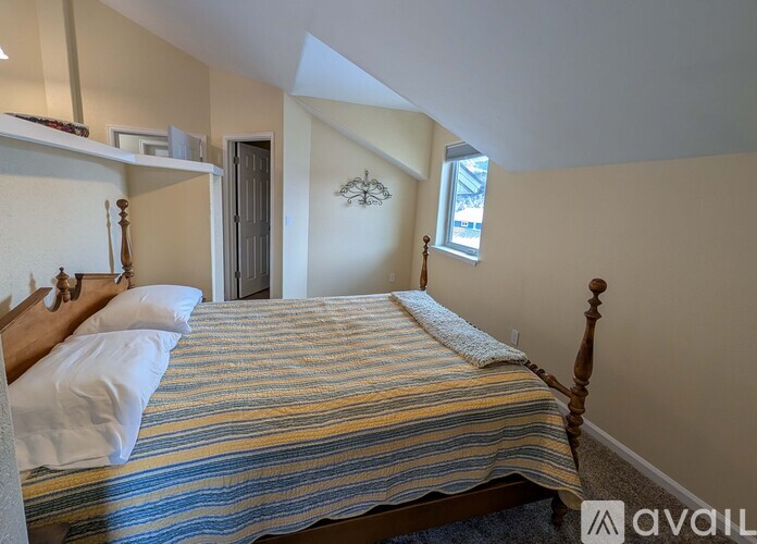 A bedroom with a bed, a window, and a shelf.