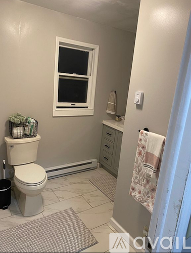 A bathroom with a toilet, a window, and a towel rack.