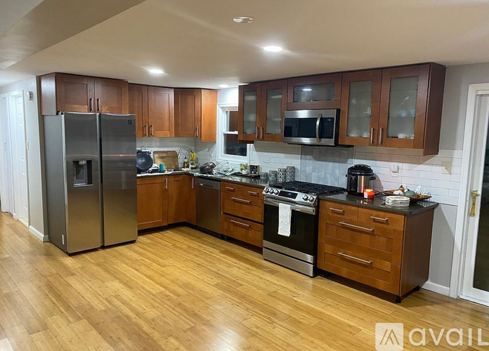 A kitchen with wooden floors and a refrigerator on the left.