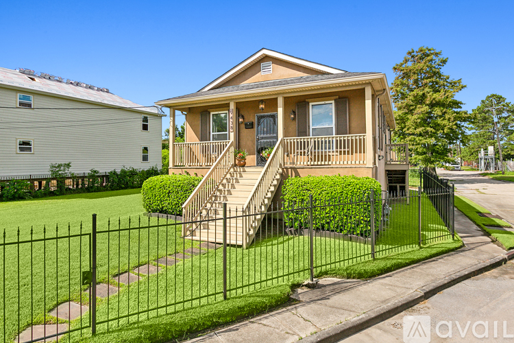 A house with a black fence and green plants in front.