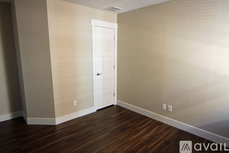 A room with a white door and wooden flooring.