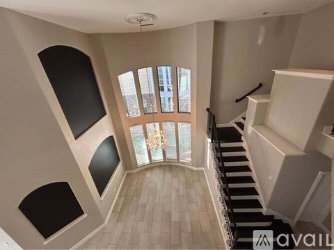 A staircase with a black railing leads to a balcony with a view of a building outside.