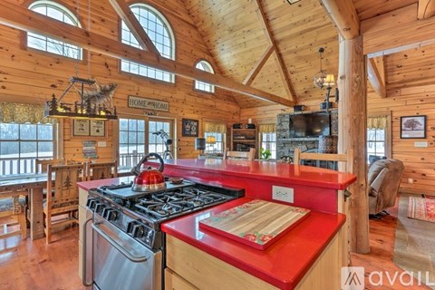 A kitchen with a red countertop and a stove with a pot on it.