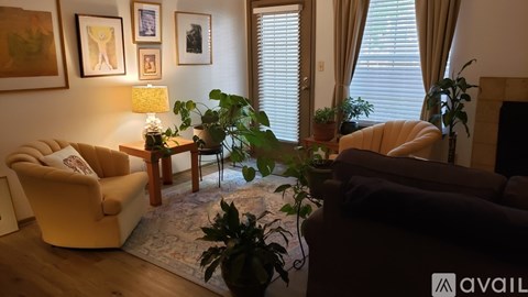 A living room with a yellow chair, a brown couch, a table with a lamp, and a potted plant.