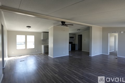 A spacious room with wooden flooring and a ceiling fan.