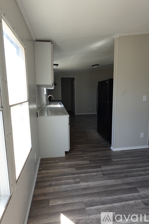 A kitchen with a black refrigerator and a white cabinet.