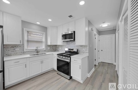 A modern kitchen with white cabinets and a black stove top oven.