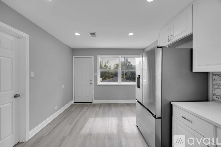 A kitchen with white cabinets and a refrigerator.