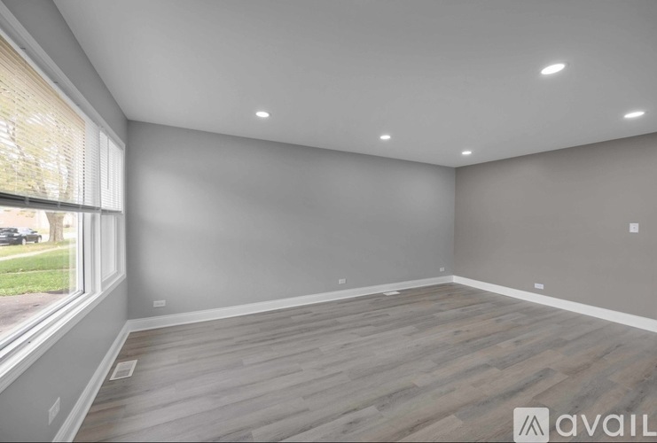 A room with wooden flooring and a window overlooking a street.