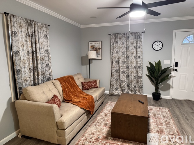 A living room with a beige couch, a wooden coffee table, and a ceiling fan.