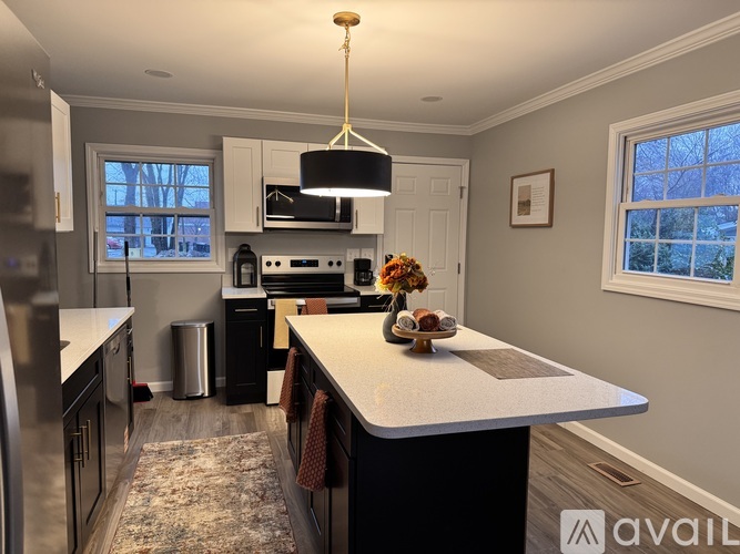 A kitchen with a large island in the middle and a window above the stove.