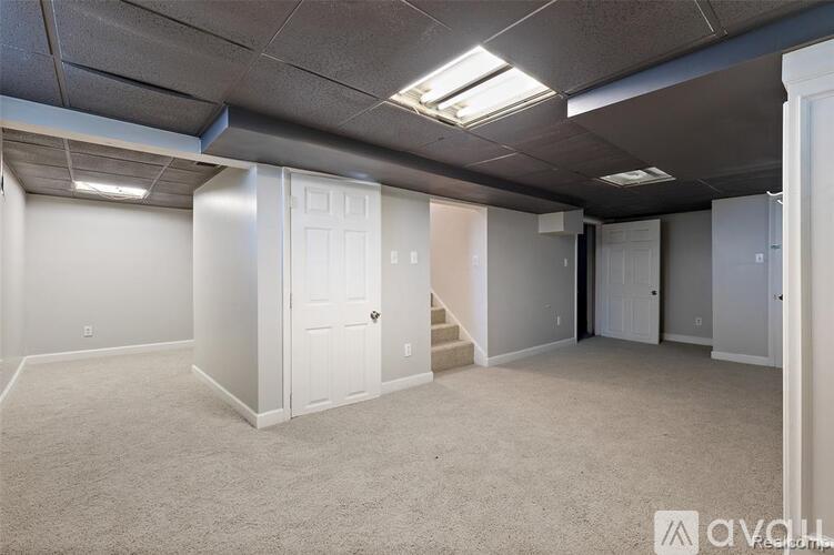 A spacious room with white walls and carpeted floor.