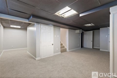 A spacious room with white walls and carpeted floor.