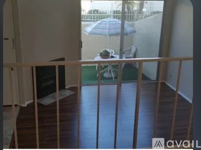 A balcony with a table and chairs and a view of a pool and umbrella.
