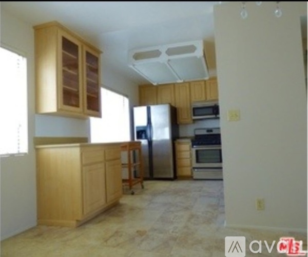 A kitchen with wooden cabinets and a stainless steel refrigerator.