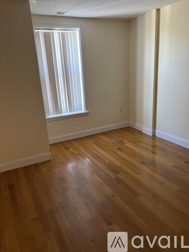 A room with wooden flooring and a window with blinds.