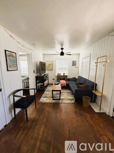 A living room with a black couch and a wooden floor.