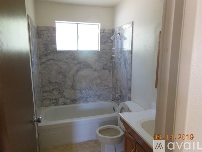 A bathroom with a marble wall and a toilet in the corner.