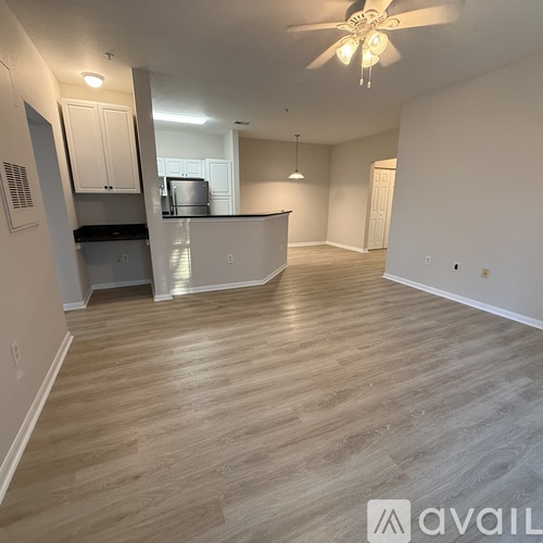 A spacious room with a kitchen area and a ceiling fan.