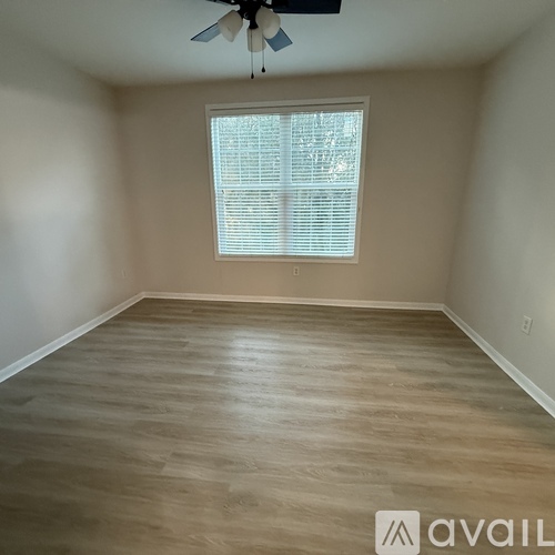 A room with a ceiling fan and a window with blinds.