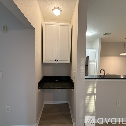 A kitchen with white cabinets and a black countertop.
