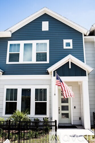 A blue house with an American flag on the front porch.