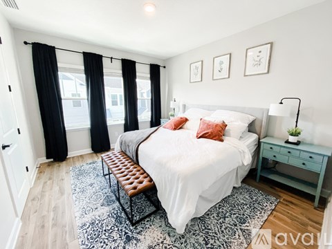 A bedroom with a bed, nightstand, and window with black curtains.