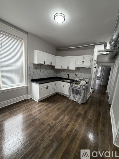 A kitchen with wooden floors and white cabinets.