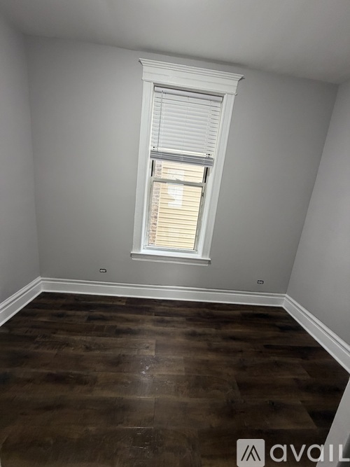 A room with a window and wooden flooring.
