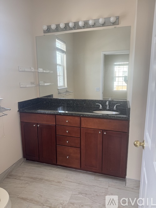 A bathroom with a vanity and a mirror with lights above it.