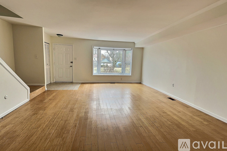 A room with wooden flooring and a window showing daylight outside.