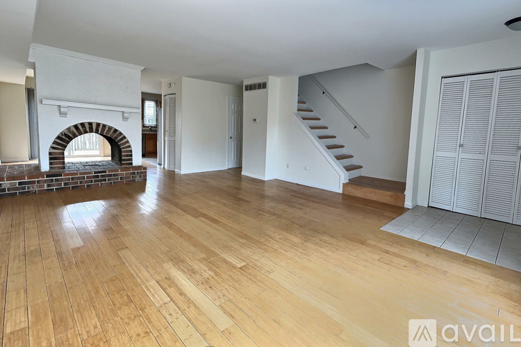 A spacious room with wooden flooring and a staircase.