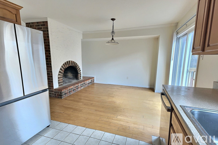A kitchen with a refrigerator, a fireplace, and a dining table.
