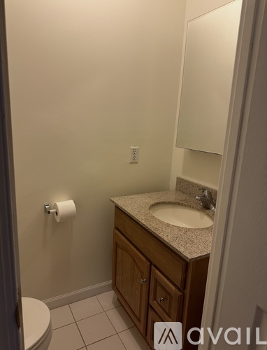 A bathroom with a toilet, sink, and mirror.