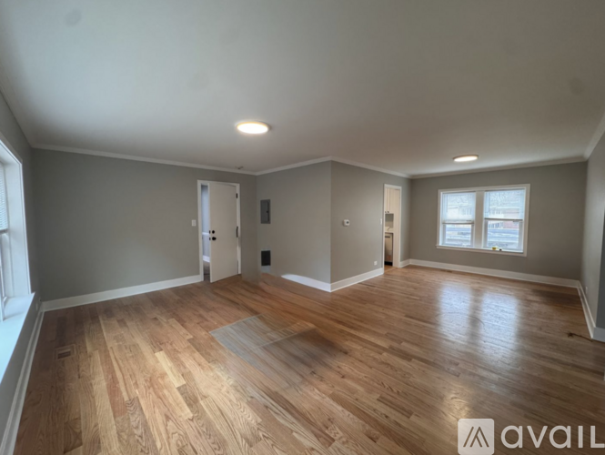 A spacious room with wooden flooring and a window.